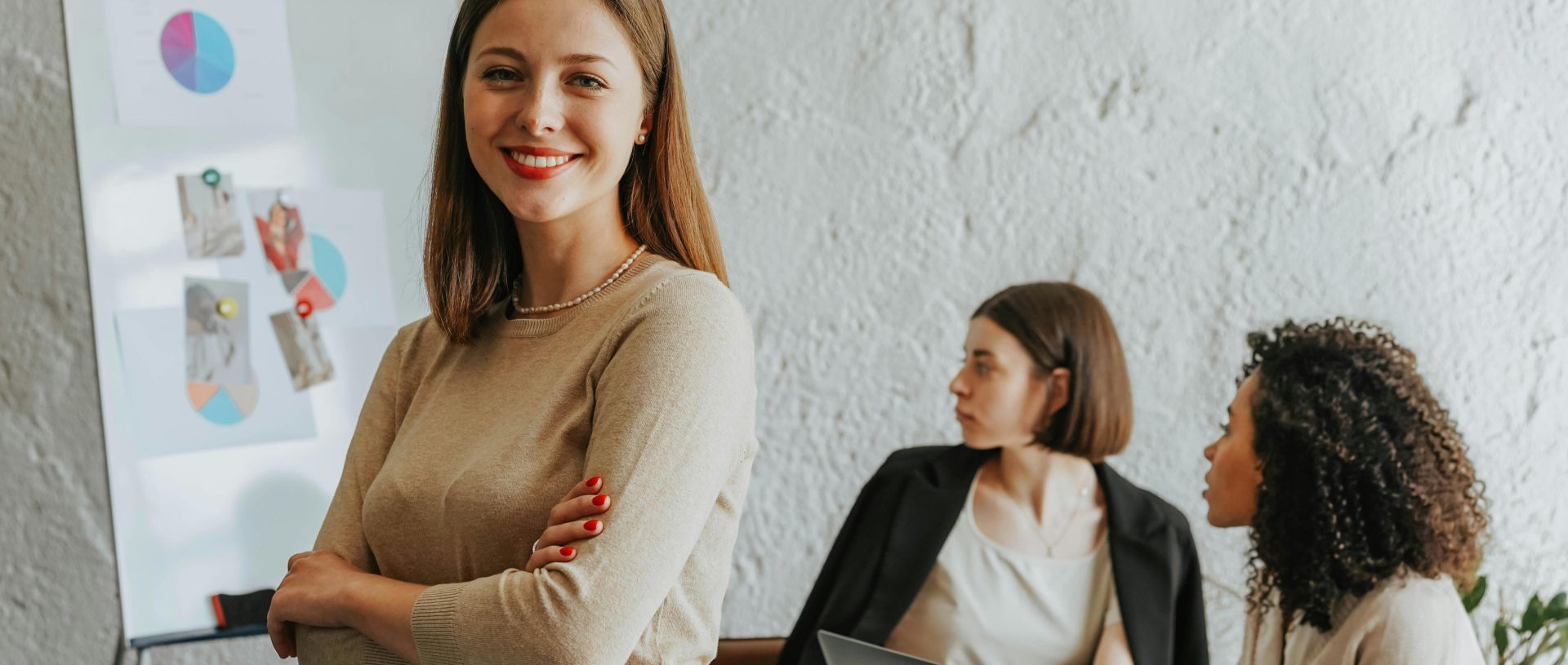 Confident woman smiling in a modern office setting with colleagues at work.